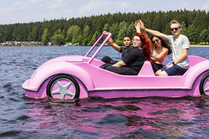 Vier Teilnehmende einer Deutsch-Israelischen Jugendbegegnung sitzen zusammen in einem Tretboot in Form eines rosa Autos.